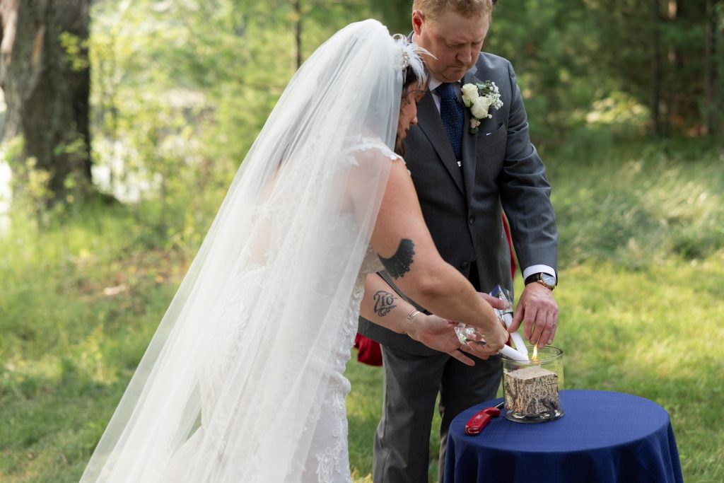 Bride and groom lighting unity candle at lakeside wedding in Hayward, WI