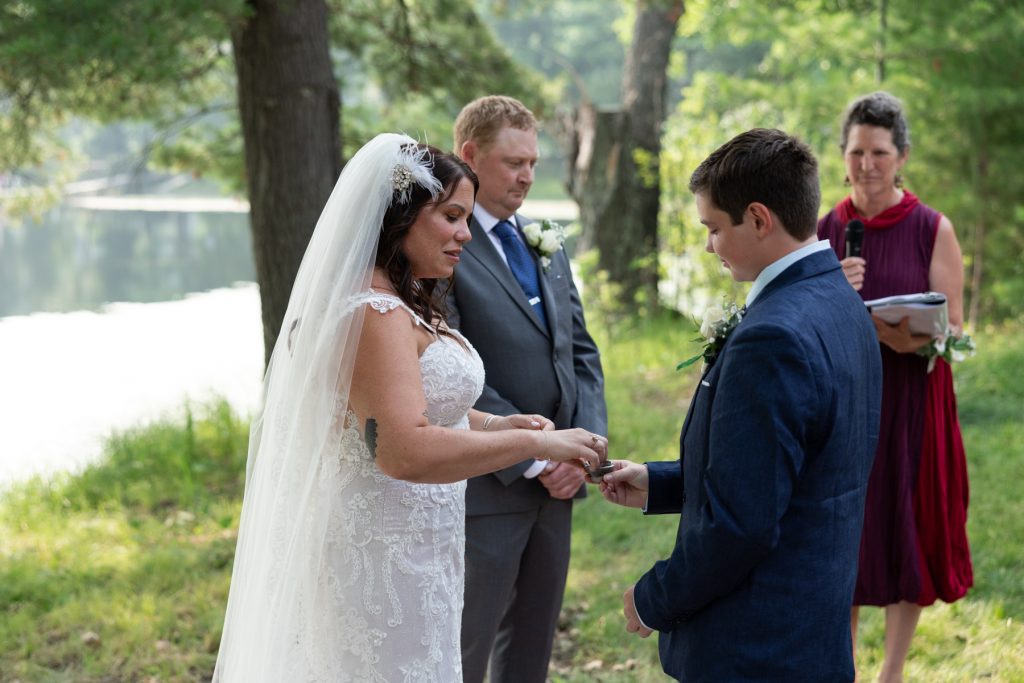 Bride and groom exchanging rings at lakeside wedding ceremony in Hayward, WI.