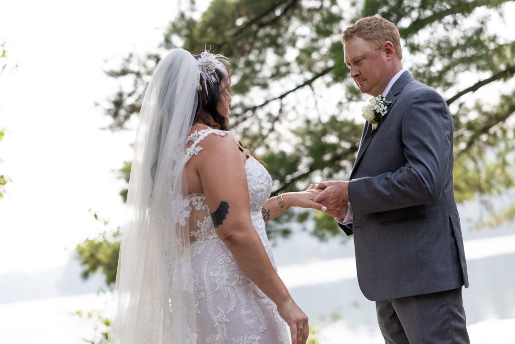 Bride and groom exchanging rings at lakeside wedding in Hayward, WI
