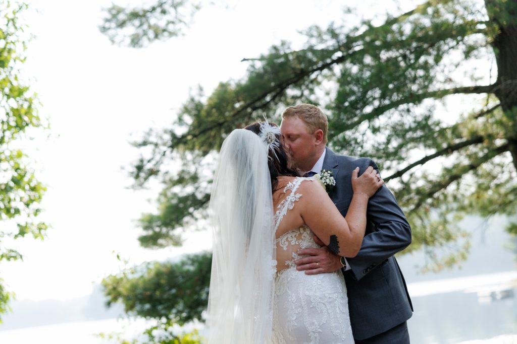 Bride and groom kissing at lakeside wedding in Hayward, WI.