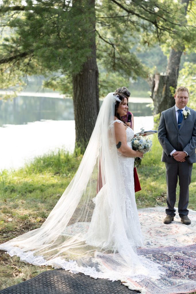 Bride in wedding dress and veil with groom at lakeside ceremony in Hayward, WI.