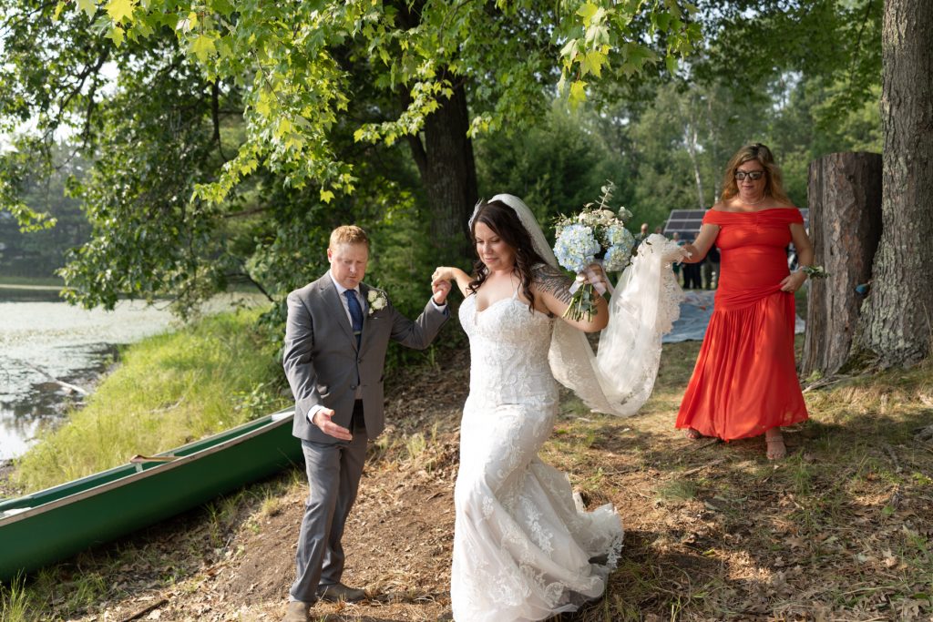 Bride and groom walking hand-in-hand by lake at Hayward, WI wedding.