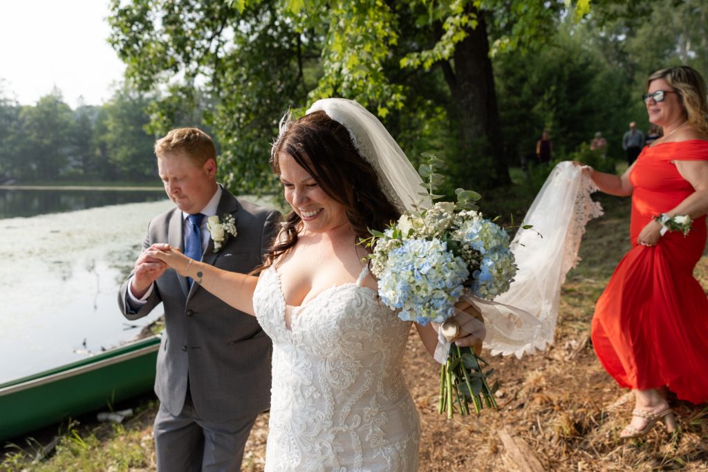 Bride and groom smiling and walking near lake at Hayward, WI wedding.