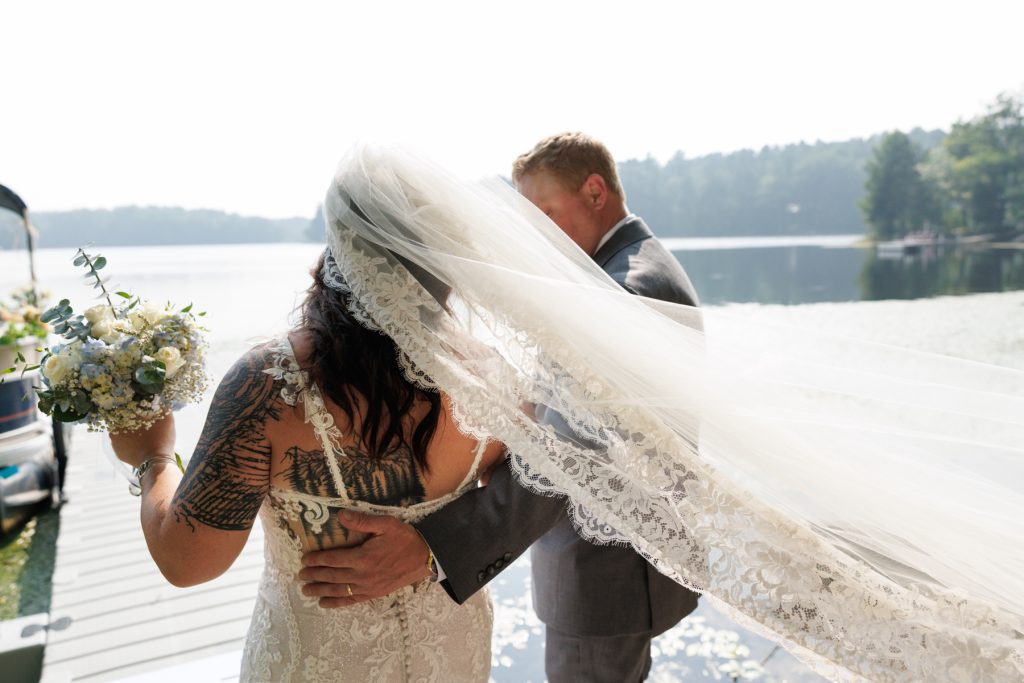Bride and groom embracing on lake dock at Hayward, WI wedding.