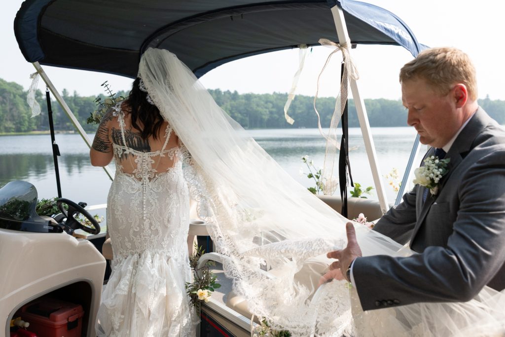 Bride arriving by pontoon boat at lakeside wedding in Hayward, WI.