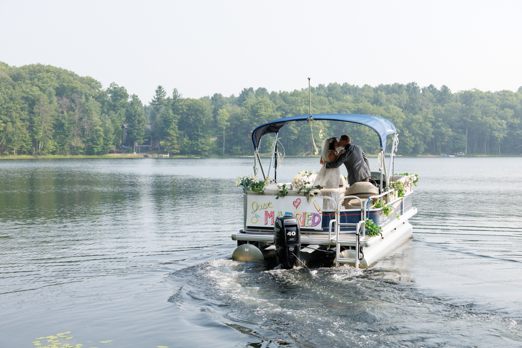Bride and groom kissing on pontoon boat at lake wedding in Hayward, Wisconsin.