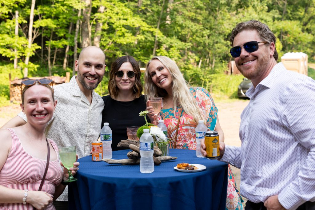 Group of wedding guests smiling at a lakeside cabin in Hayward, WI.