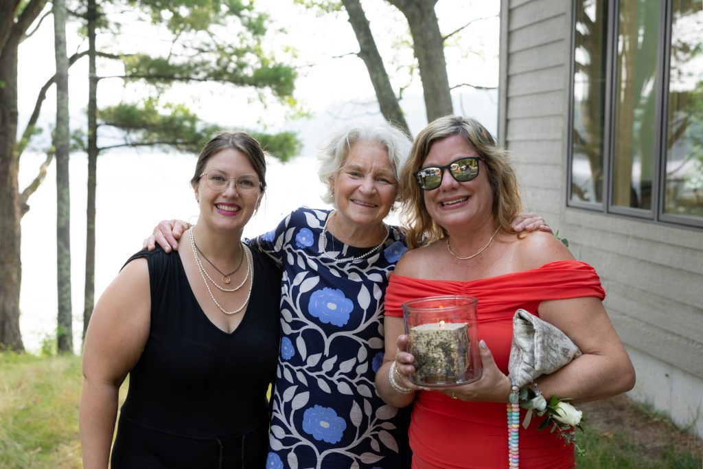 Three women smiling and posing at a lakeside wedding in Hayward, WI.