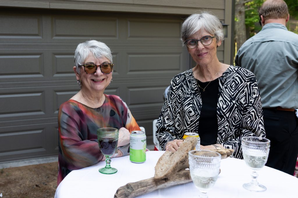 Two smiling women at a lakeside wedding in Hayward, WI, enjoying drinks and celebrating.