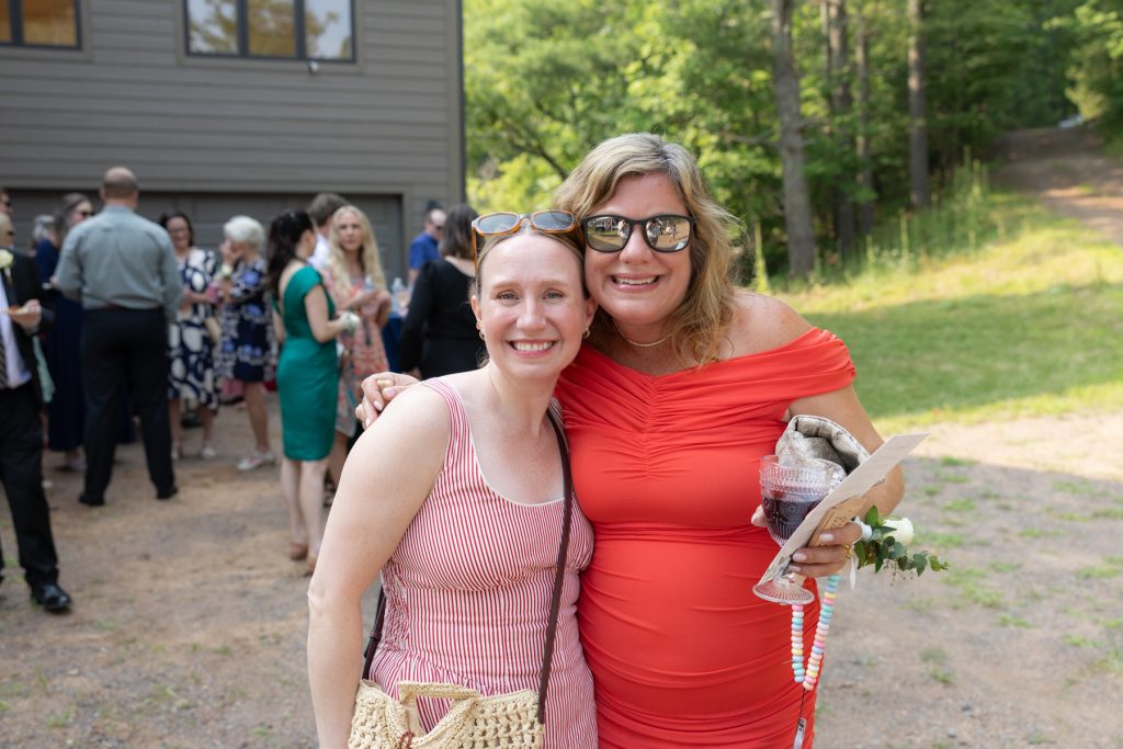 Bride and guest smiling at a lakeside wedding in Hayward, WI