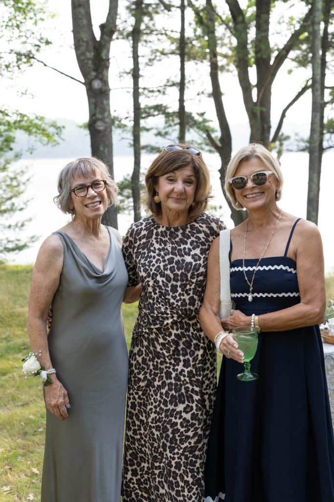 Three smiling women in dresses at a wedding in Hayward, WI