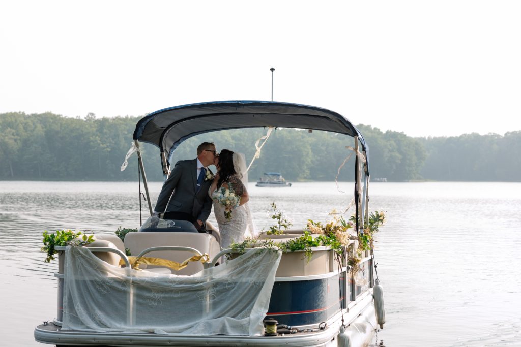 Bride and groom kissing on decorated pontoon boat at Hayward, WI lake wedding.