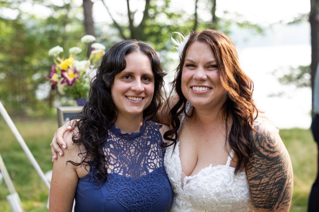 Bride and guest smiling together at a backyard wedding in Hayward, WI.