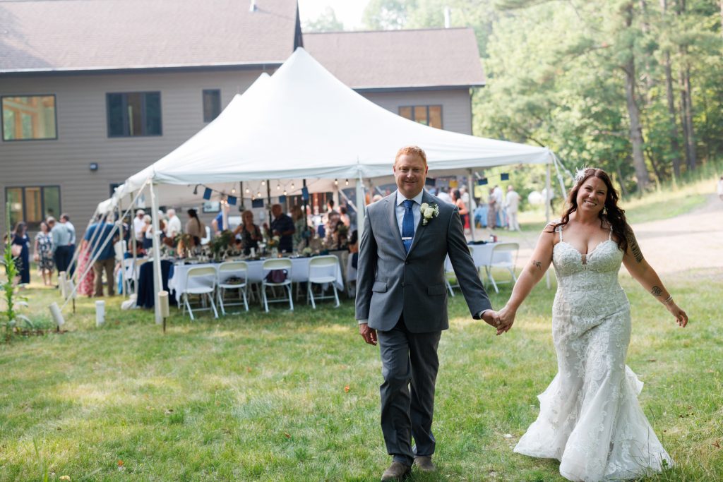 Bride and groom walking hand-in-hand at lakeside cabin wedding in Hayward, WI