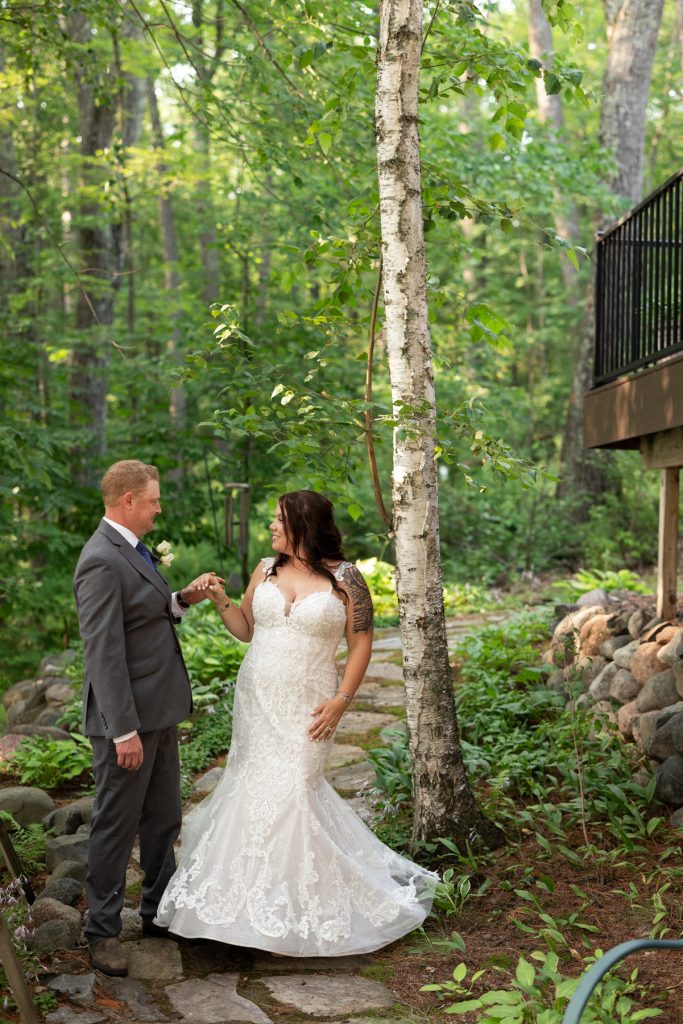 Bride and groom embracing on stone path at lakeside cabin wedding in Hayward, WI