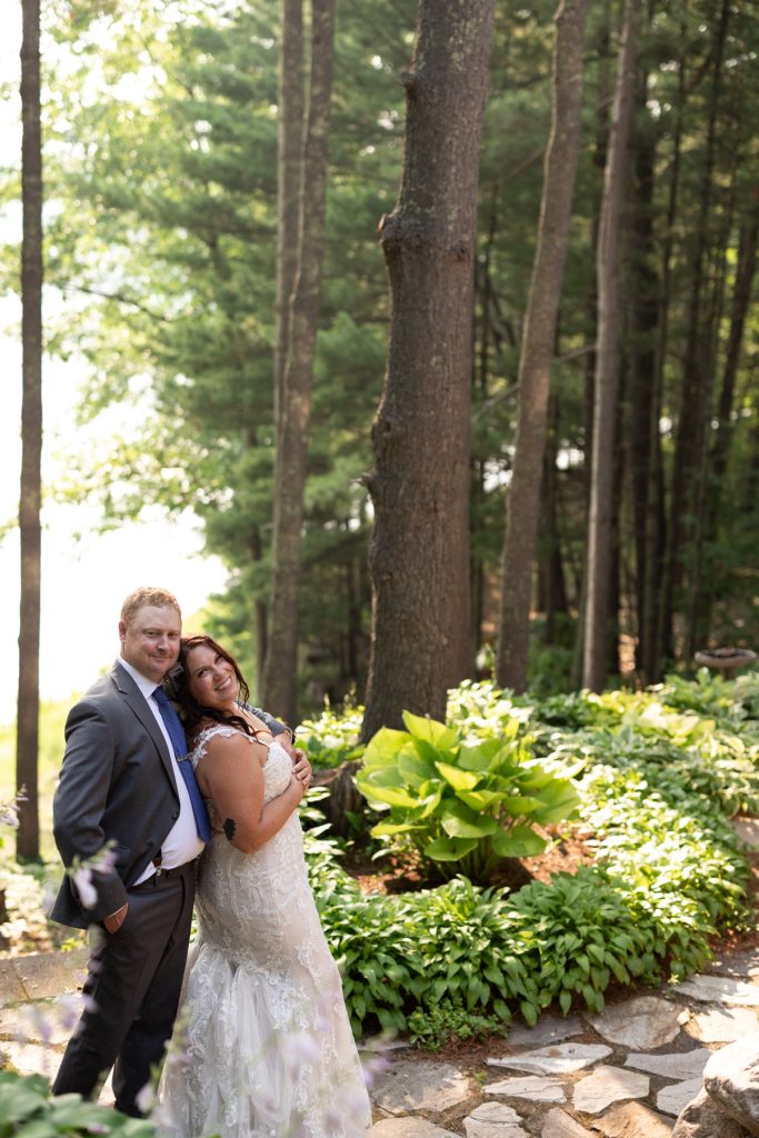 Bride and groom embracing in Hayward, WI lakeside cabin wedding setting.