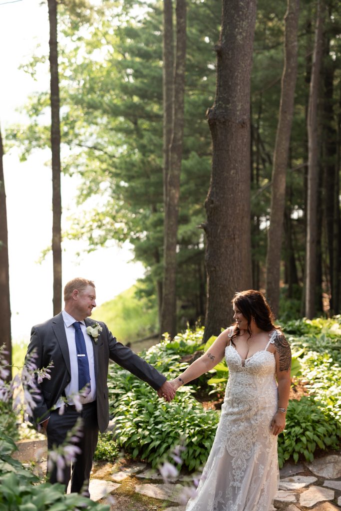 Bride and groom holding hands in lakeside forest, Hayward, WI wedding photography.