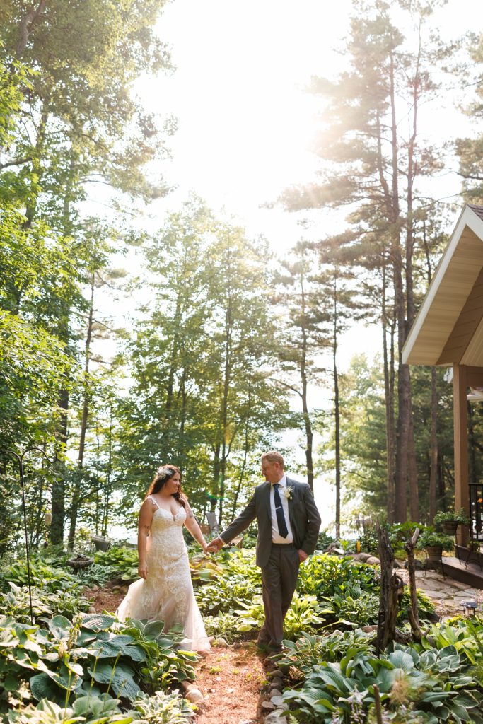 Bride and groom walking hand-in-hand at a lakeside wedding in Hayward, WI.