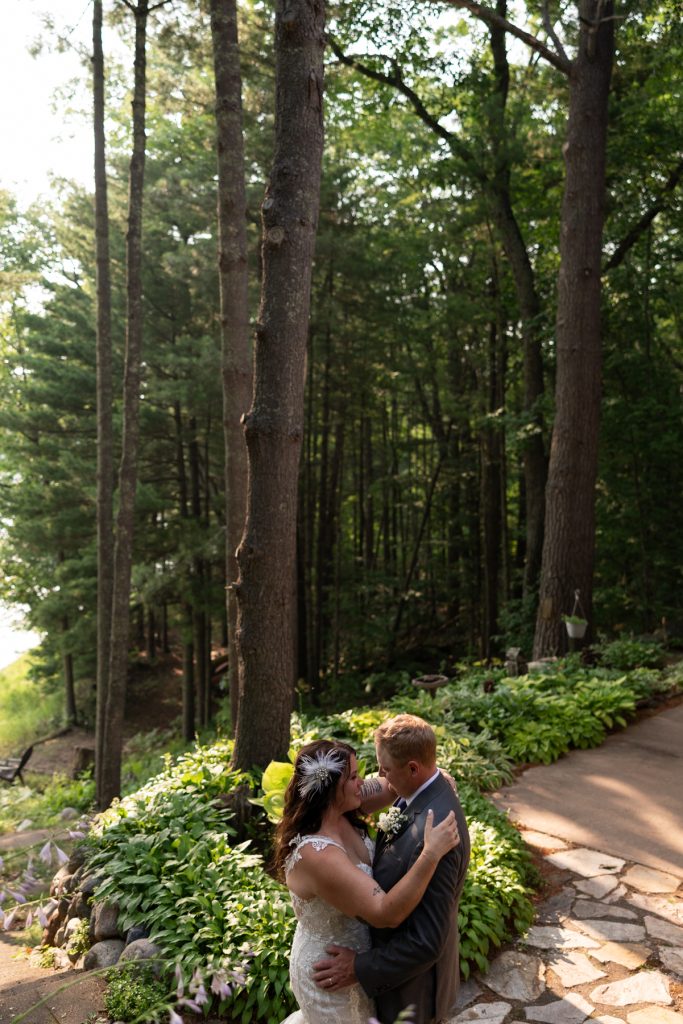 Bride and groom embracing in lakeside backyard wedding in Hayward, WI.