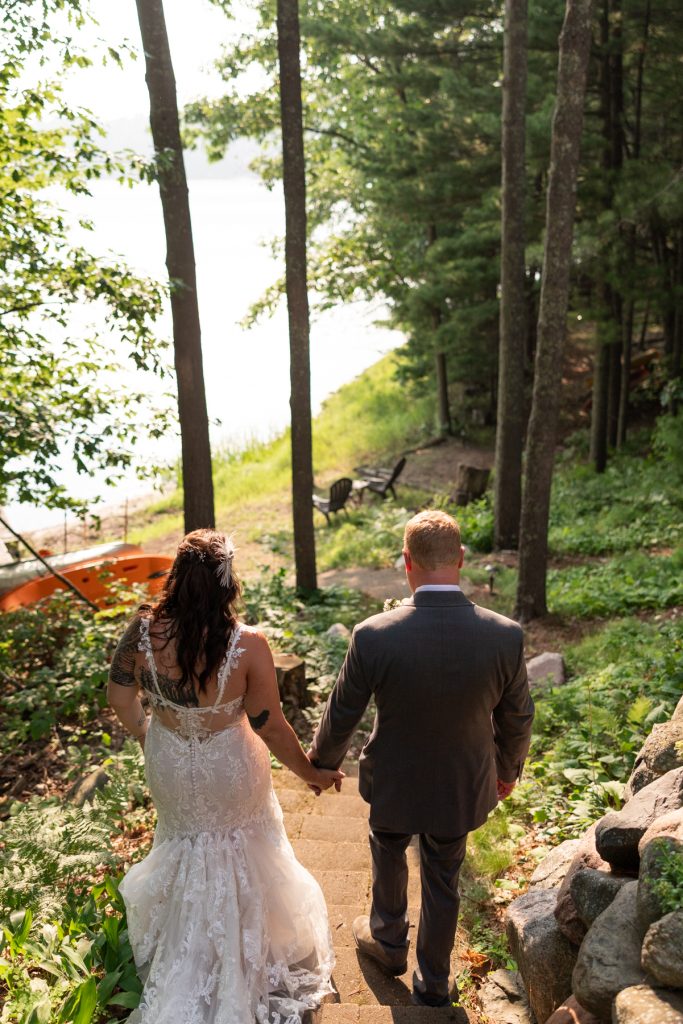 Bride and groom walking hand-in-hand overlooking lake at Hayward, WI wedding.