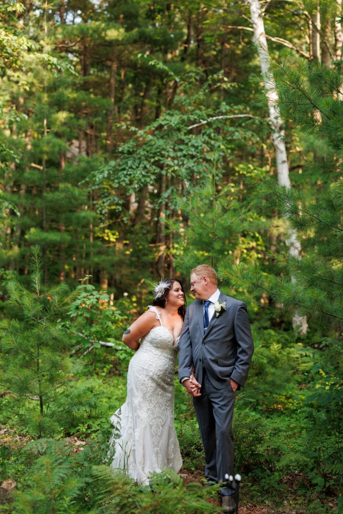 Bride and groom holding hands in wooded area at Hayward, WI wedding.