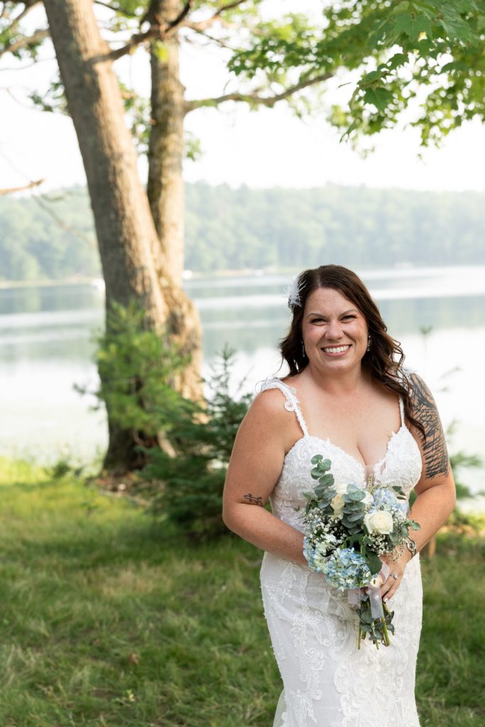 Bride in wedding dress holding bouquet by lake in Hayward, WI