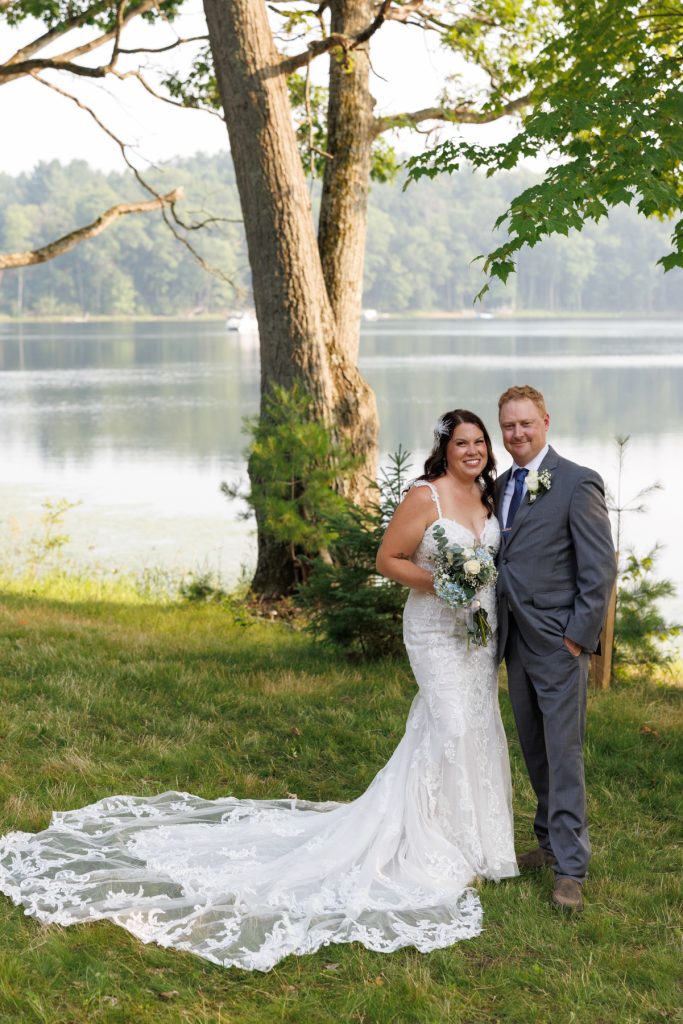 Bride and groom posing for wedding photos by the lake in Hayward, WI