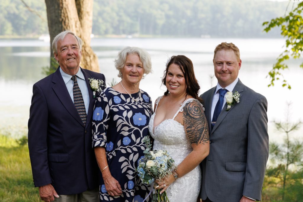 Bride and family posing for wedding photo by the lake in Hayward, WI.