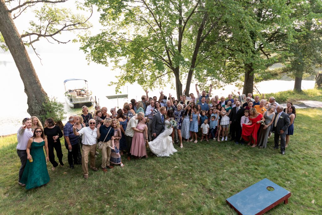 Wedding group photo at lakefront cabin in Hayward, WI, with pontoon boat in background.