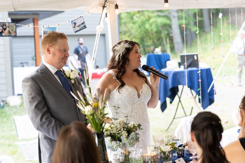 Bride and groom speaking into microphone at lakeside wedding reception in Hayward, WI
