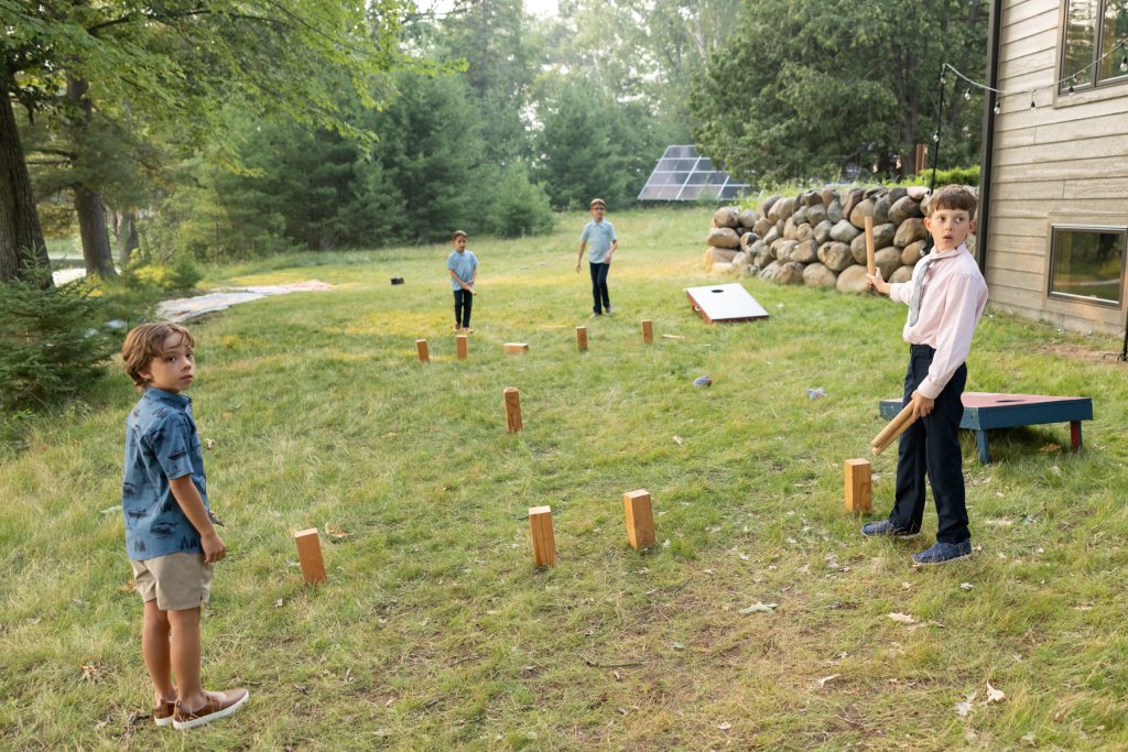 Children playing cornhole game at a lake wedding in Hayward, WI.