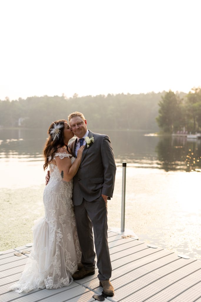 Bride and groom embracing on lakefront dock at Hayward, WI wedding