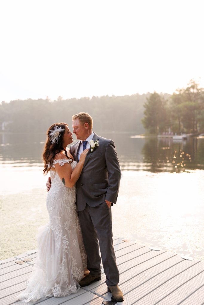Bride and groom embracing on lake dock at Hayward, WI wedding.