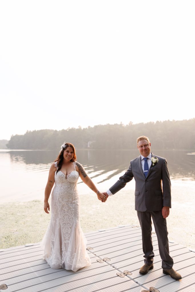 Bride and groom holding hands on lakefront dock at Hayward, WI wedding.