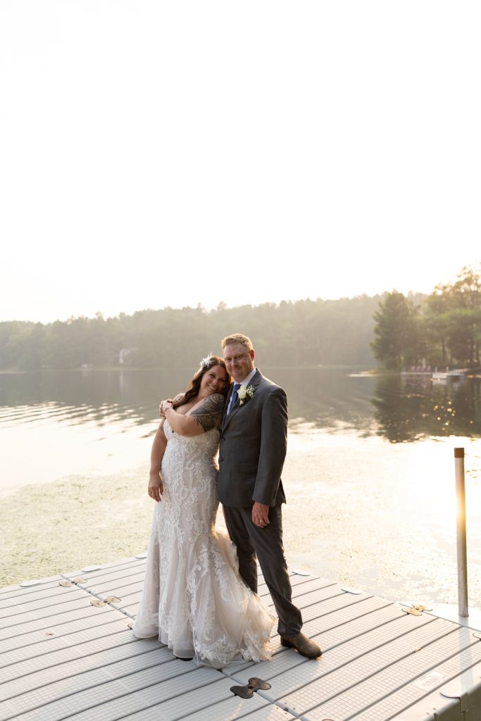 Bride and groom posing on lake dock at Hayward, WI wedding.