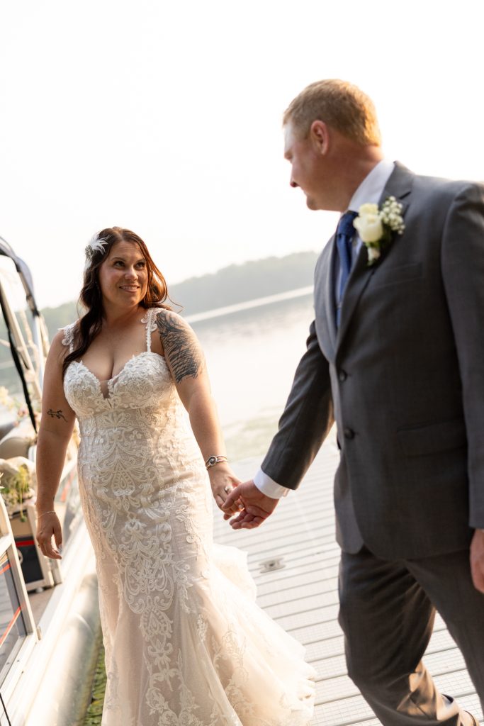 Bride and groom holding hands on dock at Hayward, WI lake wedding.