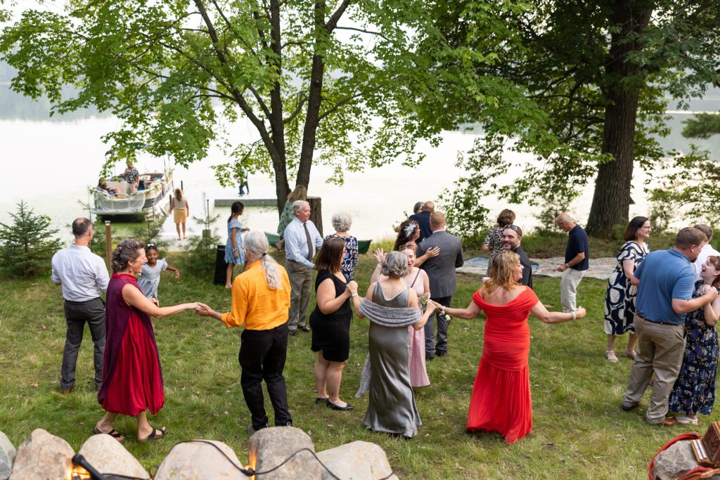 Backyard wedding reception on a lake in Hayward, WI, with guests dancing and a pontoon