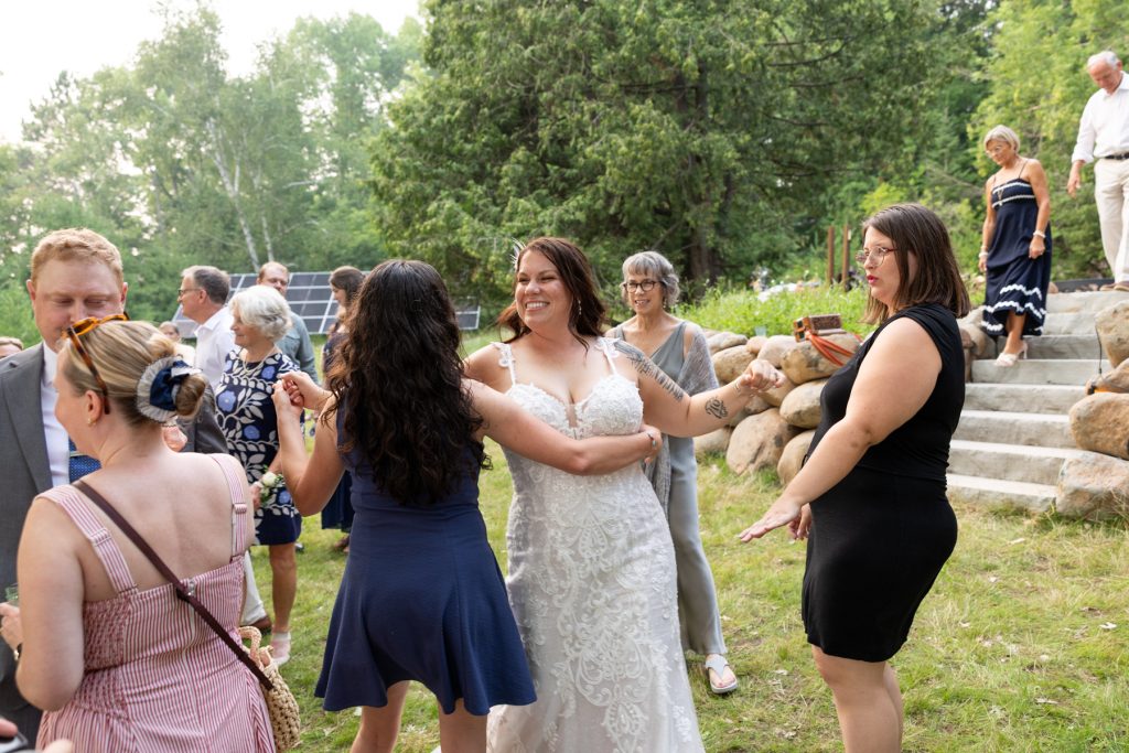 Bride in wedding dress dancing with guests at a lakeside wedding in Hayward, WI