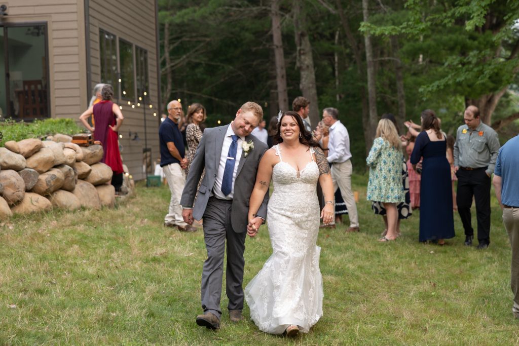 Bride and groom walking hand-in-hand at a lakeside wedding in Hayward, Wisconsin.