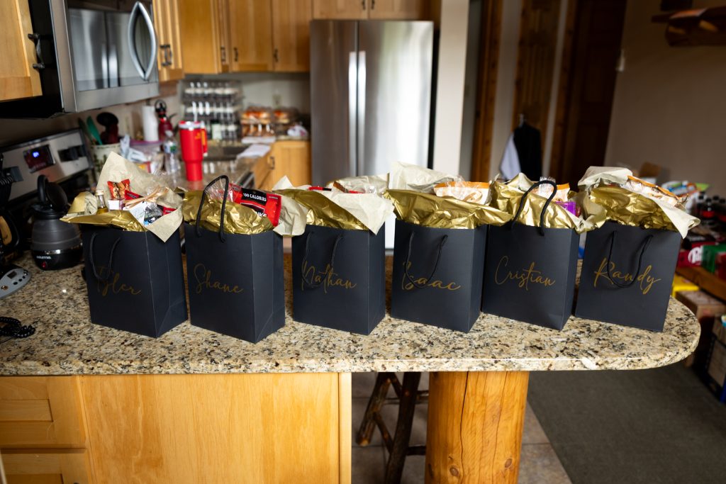 Line of personalized gift bags with gold lettering, likely wedding favors, displayed on a kitchen