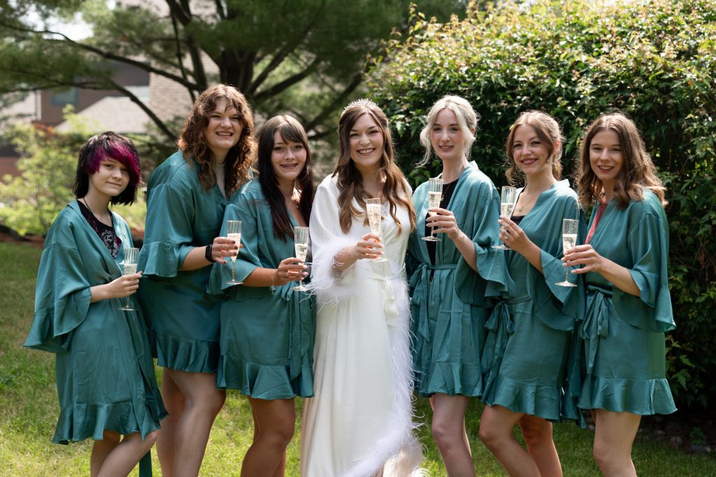 Bride and bridesmaids in matching robes and champagne glasses celebrating a Wisconsin wedding, captured