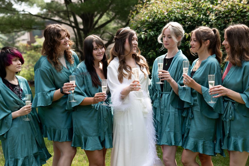 Bride and bridesmaids in matching robes celebrating with champagne, capturing a joyful moment of wedding