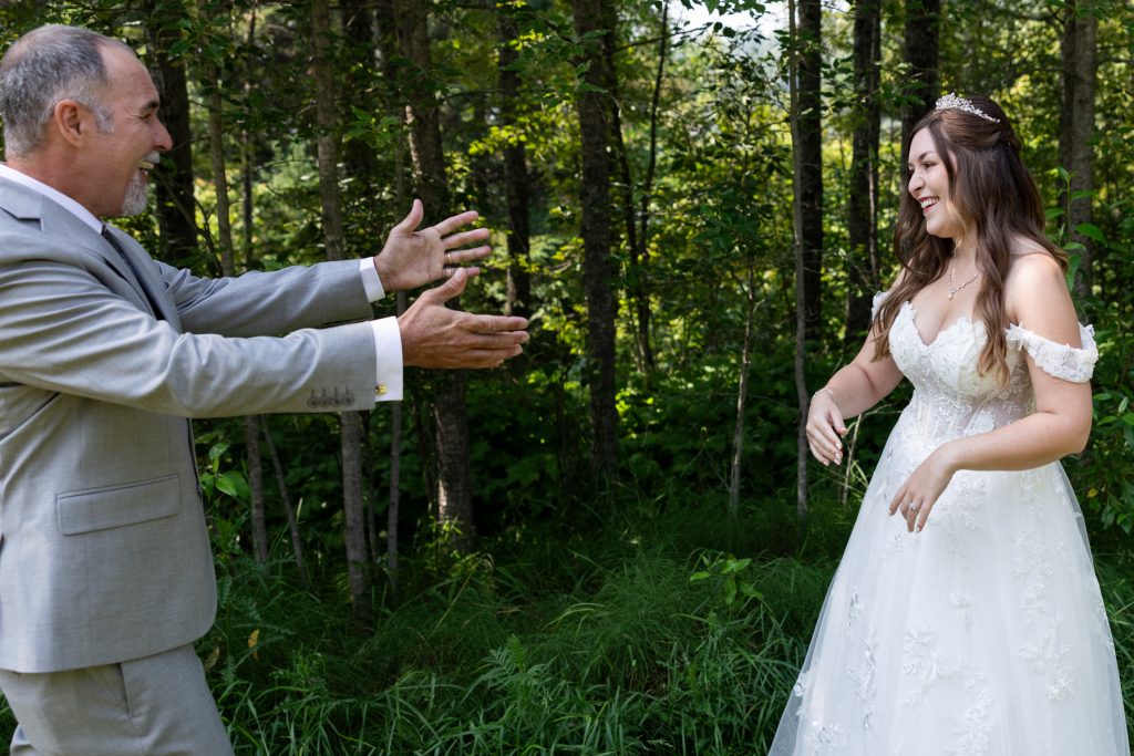 Bride and groom sharing a joyful first look in a wooded setting, captured by Beau