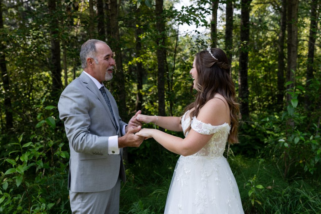 Bride and groom's father holding hands in a forest setting, captured by Wisconsin and Minnesota