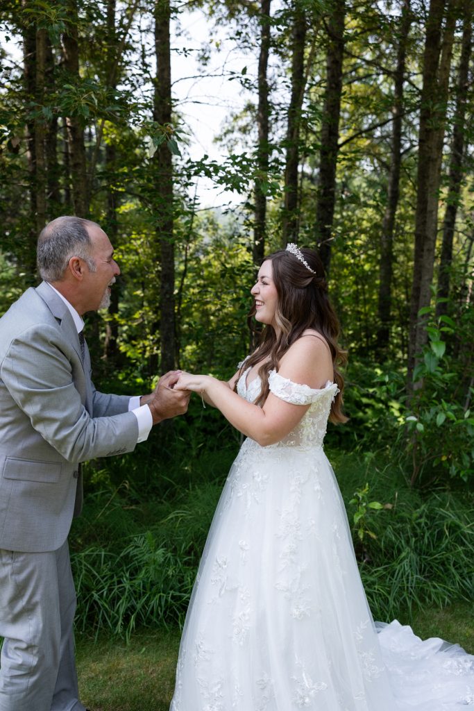 Bride and father sharing an emotional first look moment in a wooded setting, captured