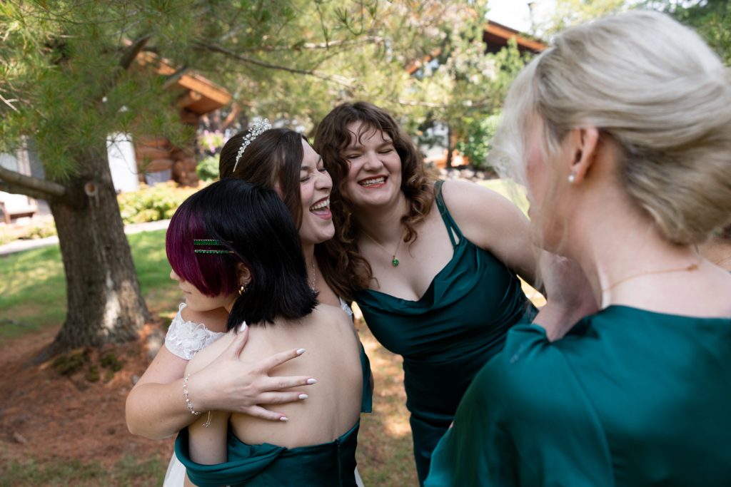 Bride embracing joyful bridesmaids in green dresses during a Wisconsin wedding celebration, captured by Beau