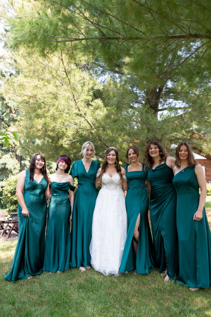Bride poses with her bridesmaids in emerald green dresses during a Wisconsin wedding photography session