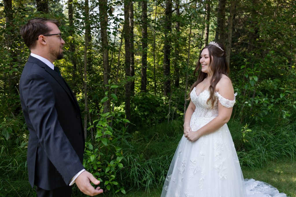 Bride in a flowing wedding gown and groom in a suit share an emotional first