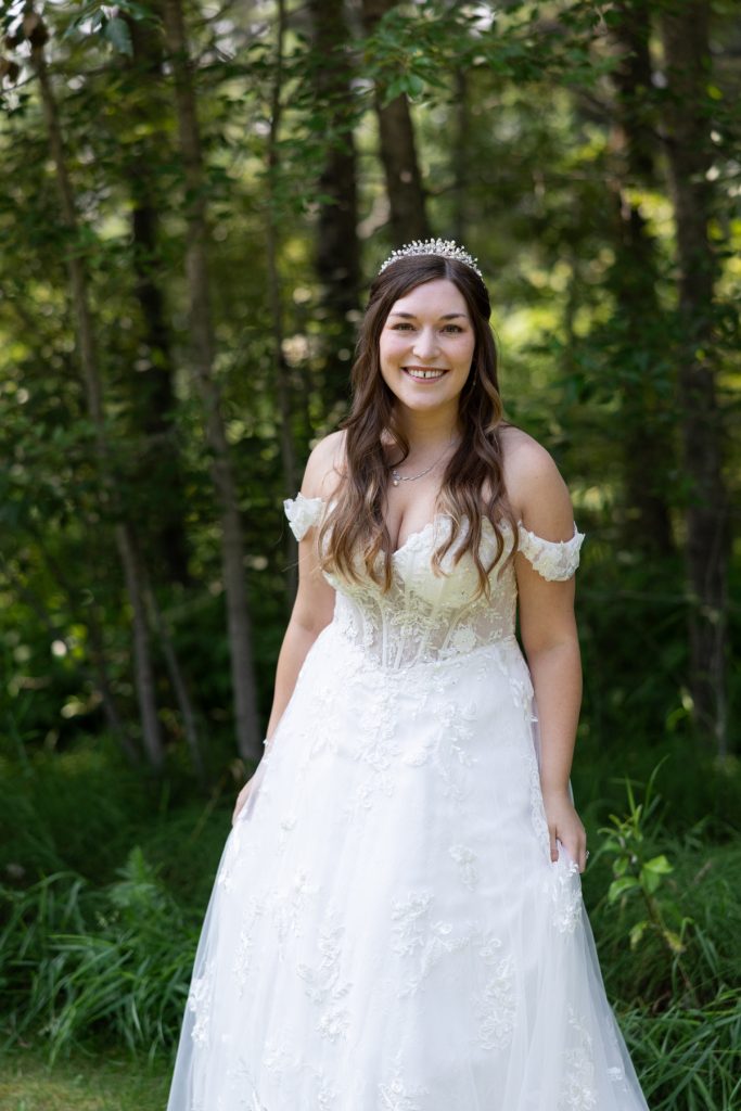 Bride in a detailed white wedding dress and sparkling tiara smiles for a portrait