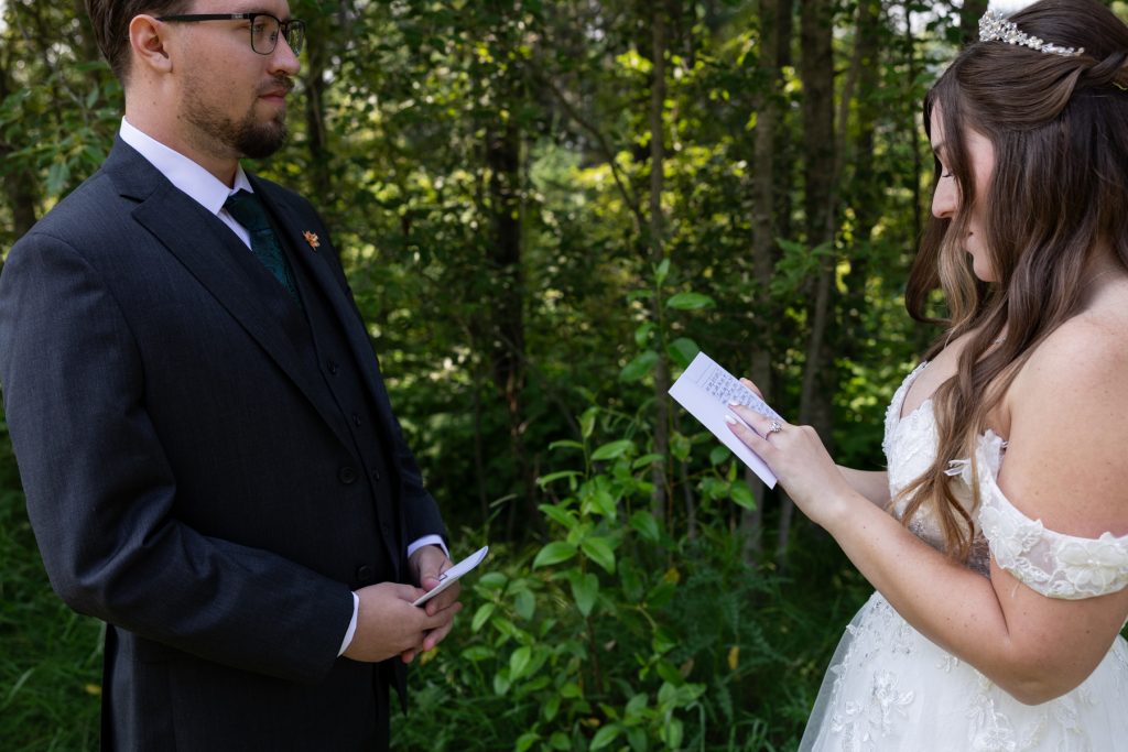 Bride and groom exchanging vows in a wooded setting, captured by Beau Petersen Photography, showcasing